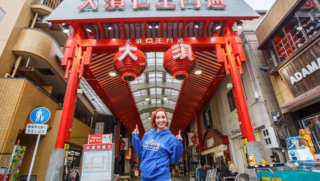 Elly in Osu Shopping Street Our CEO, Elly, smiling and pointing to the sign for Osu Shopping Street.