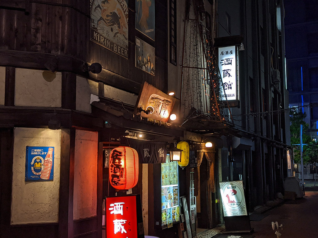 A Japanese izakaya lit up with lanterns and signs at night.