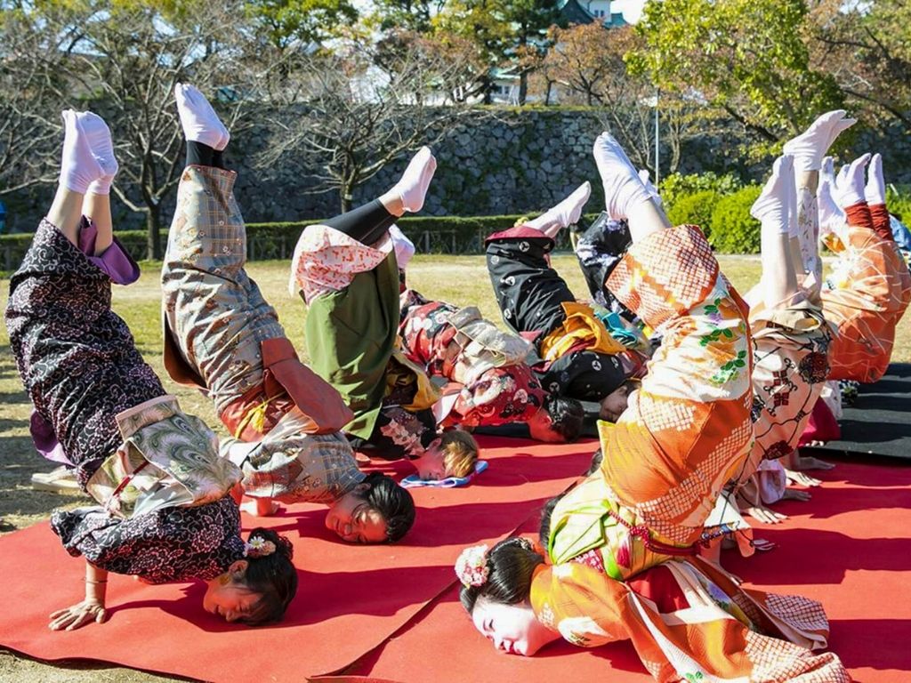 Elly (green and black Kimono), the Maiko “Usagi-chan” and others in Kimono doing the Kin no Shachihoko pose. Image via Yattokame Bunkasai.