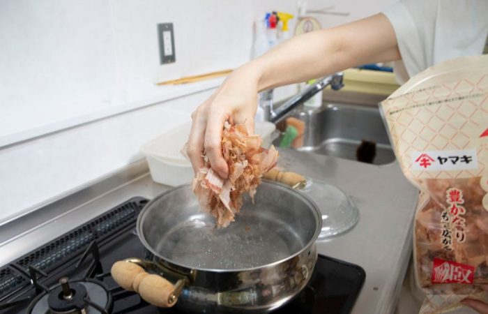 Adding bonito flakes to water to make fish stock