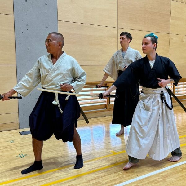 Inuyama Iaido Lesson Inuyama Iaido Lesson with the instructor and two people dressed in black and white hakama, mid-draw.