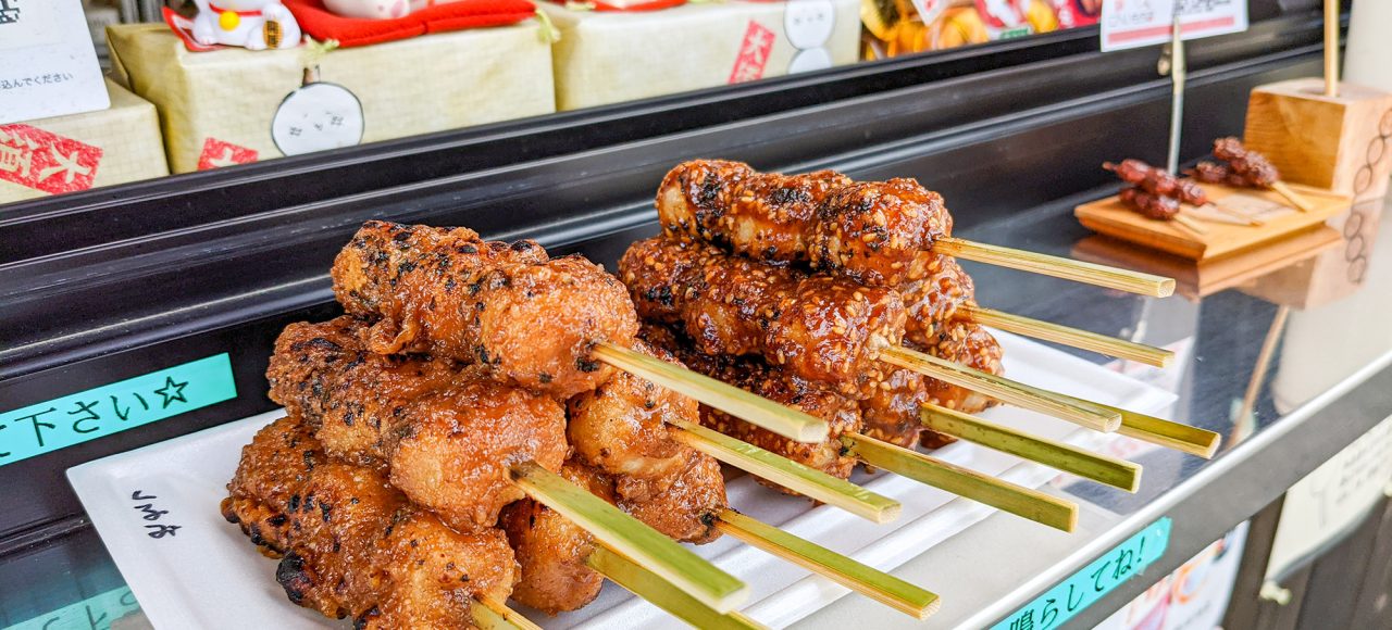 Osu-Street-Food Gohei mochi skewers lined up on a plate at a food stall.
