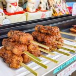 Osu-Street-Food Gohei mochi skewers lined up on a plate at a food stall.
