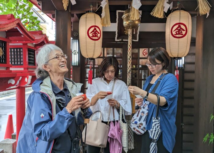 Three women reading their paper fortunes at a Japanese shrine.