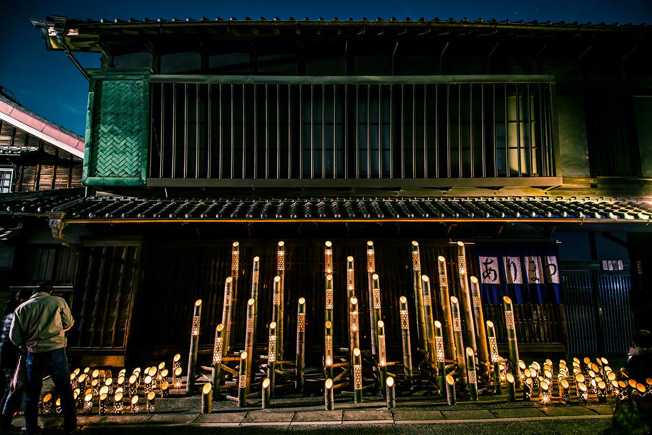 Lit-up bamboo shoots outside of a traditional Japanese storefront.
