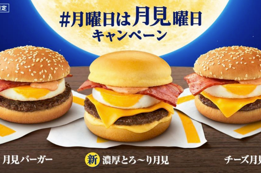 Three tsukimi burgers with runny egg yolk against a night sky and full moon background.