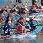 Asian Games featured image 2 Dragon boat racing on a river with half the players in focus and half blurred.
