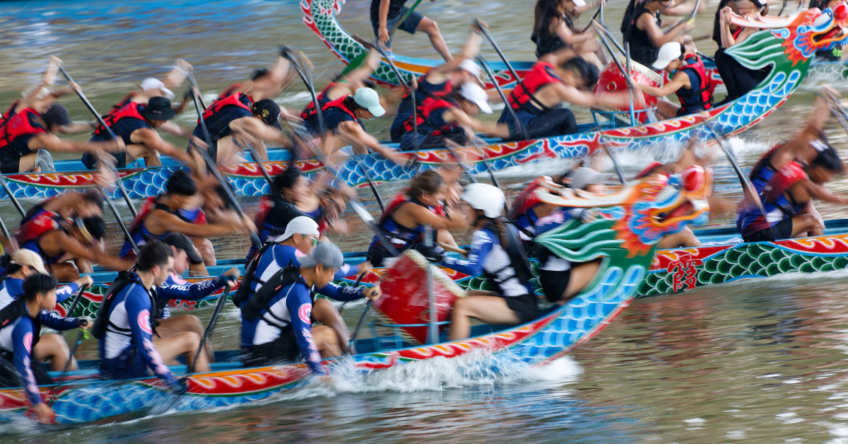 Dragon boat racing on a river with half the players in focus and half blurred.
