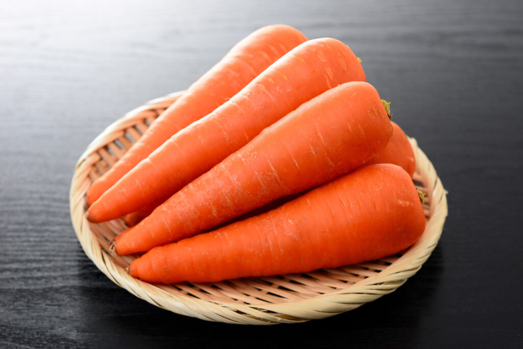 Six carrots set atop a woven bamboo mat.