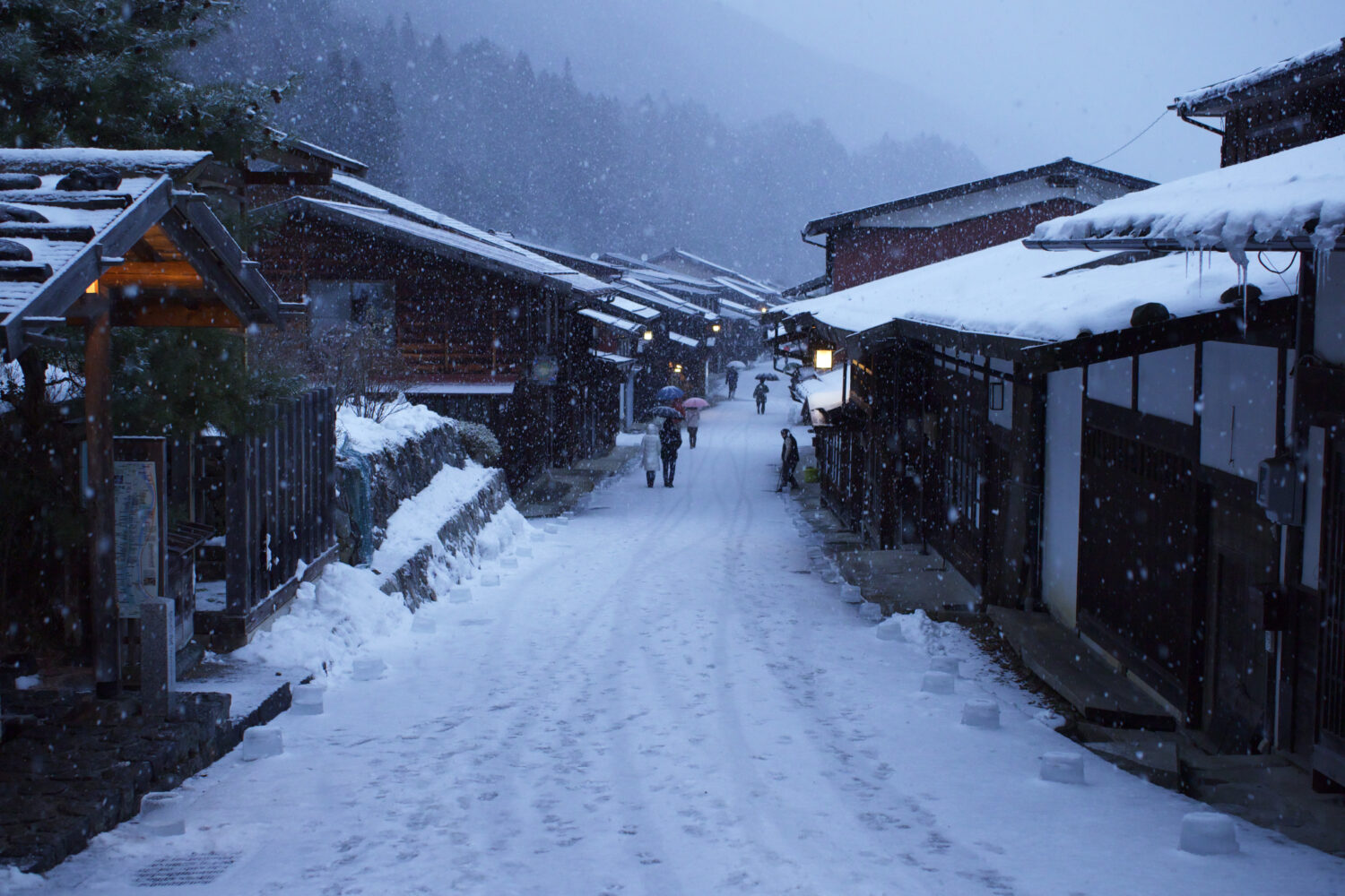 The post town of Naraijuku, with the pathway and wooden shop's roofs covered in snow.
