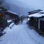 The post town of Naraijuku, with the pathway and wooden shop's roofs covered in snow.