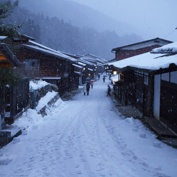 The post town of Naraijuku, with the pathway and wooden shop's roofs covered in snow.
