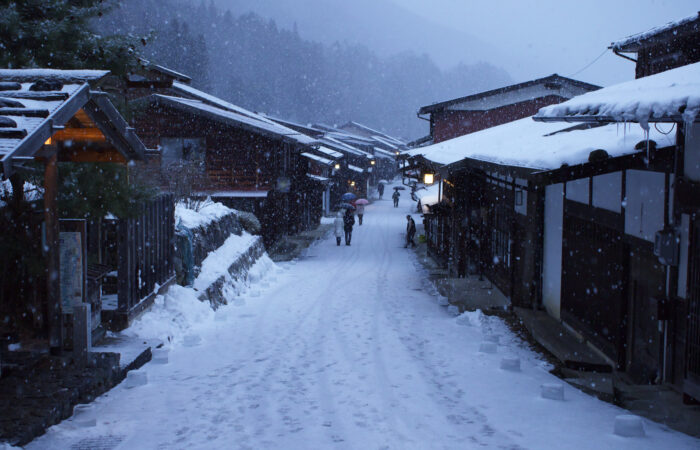 The post town of Naraijuku, with the pathway and wooden shop's roofs covered in snow.