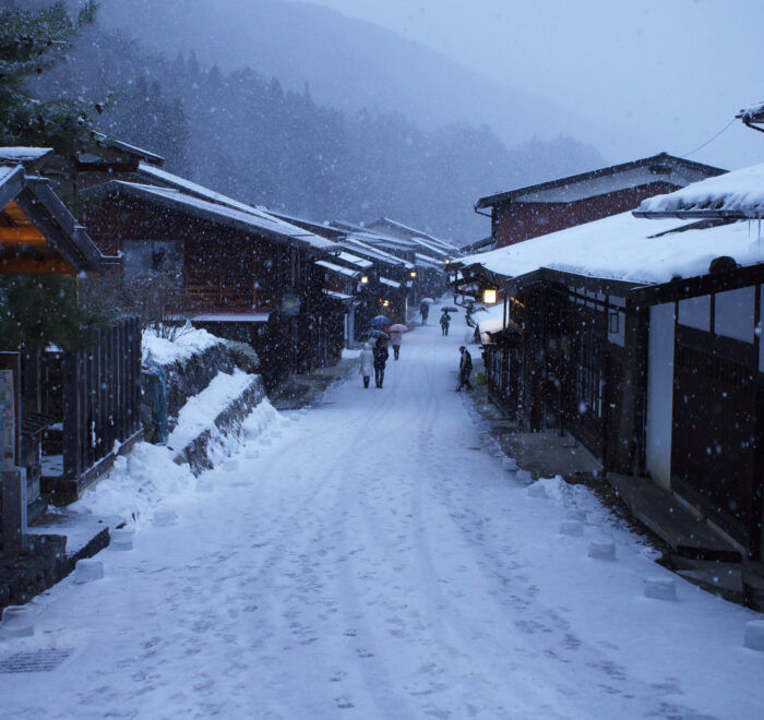 The post town of Naraijuku, with the pathway and wooden shop's roofs covered in snow.