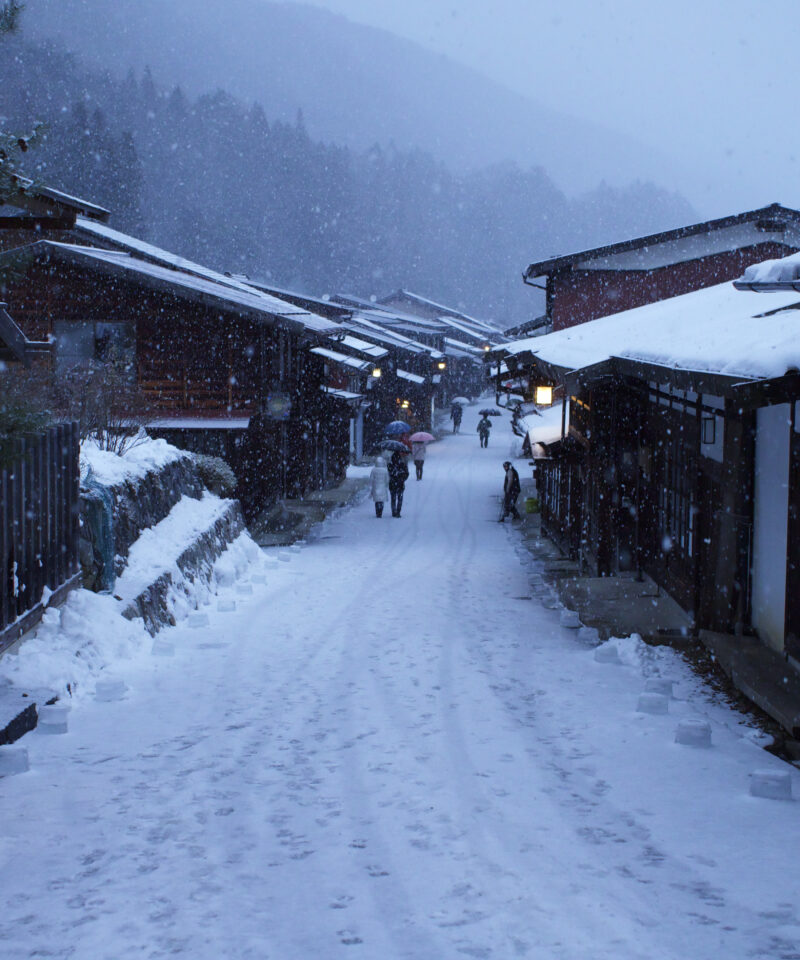 The post town of Naraijuku, with the pathway and wooden shop's roofs covered in snow.