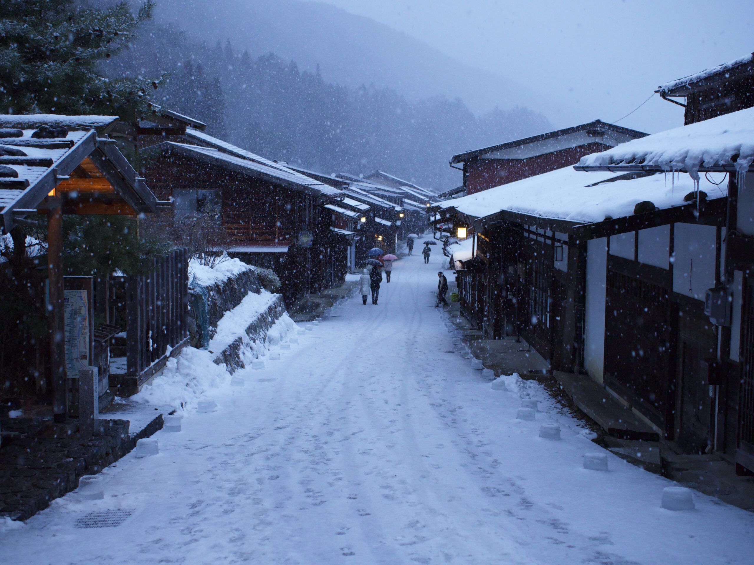 The post town of Naraijuku, with the pathway and wooden shop's roofs covered in snow.